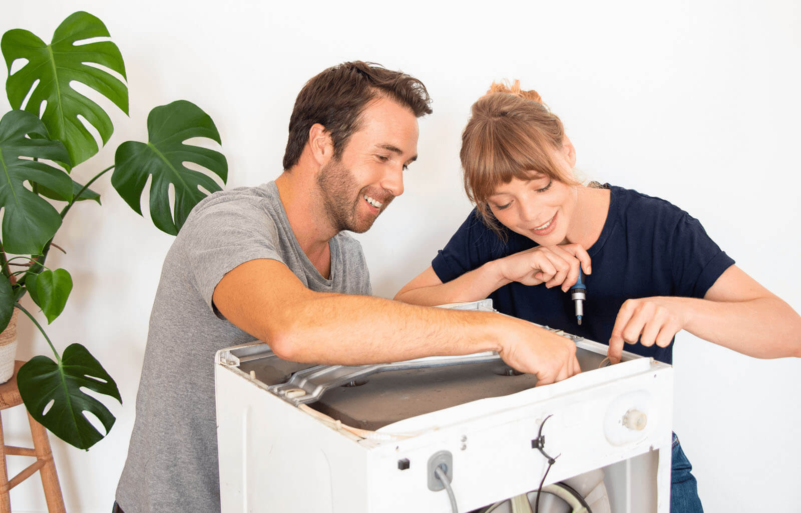 Photographie d'un homme et d'une femme qui réparent leur machine à laver